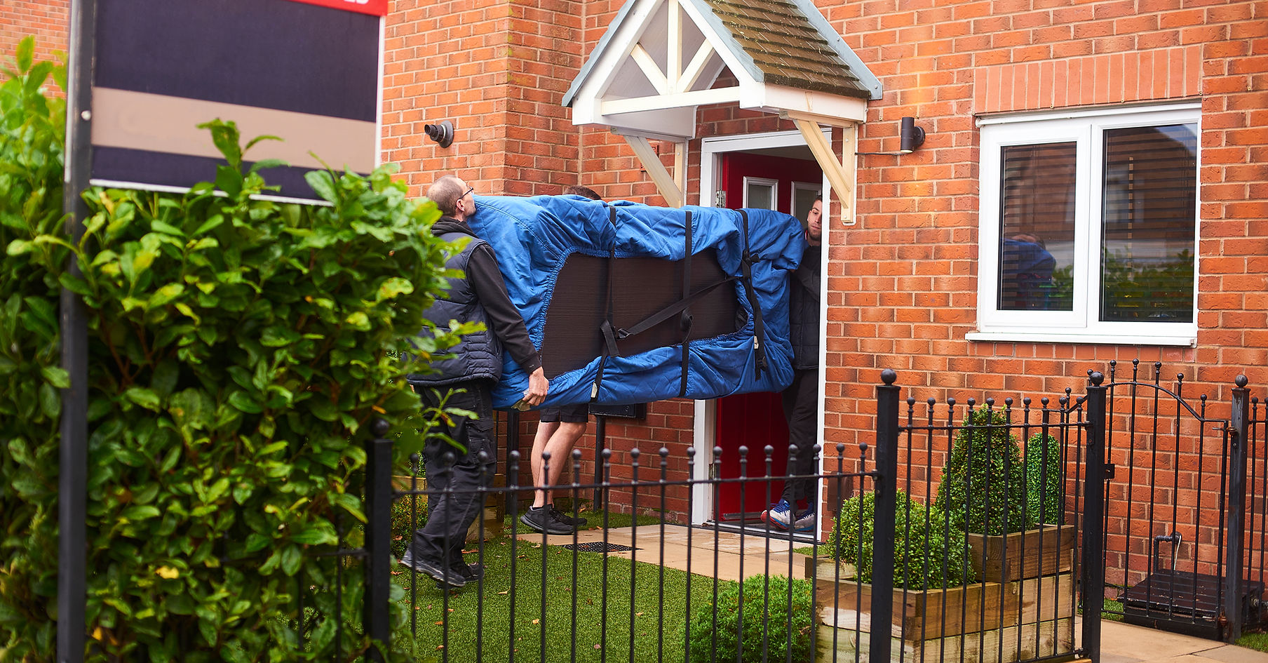 Clearance team carrying wrapped furniture into a Lancashire home
